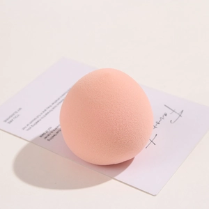 Pink egg-shaped makeup sponge for dry and wet use on a minimalist decorative card