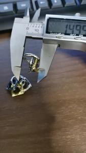 Digital caliper measuring the 14.99mm outer diameter of a metallic hoop earring