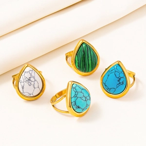 Detailed close-up of four gold teardrop rings with colored stones on white fabric