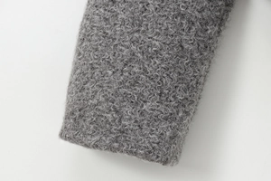 Détail du tissu bouclé gris et de la manchette en peluche sur la veste courte