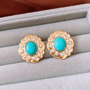 Dettaglio di orecchini vintage a fiore in oro con pietra turchese e strass scintillanti