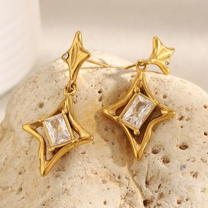 Detail of 18K gold-plated star earrings with rectangular crystal on beige rock