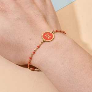 Gemini constellation charm bracelet in gold and red enamel worn on a model's wrist
