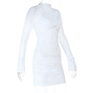 Dettaglio del tessuto in pizzo floreale bianco e del nodo sul mini abito a maniche lunghe