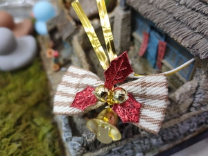 Macro detail of beige houndstooth bow with red leaves and gold bells for pet accessories