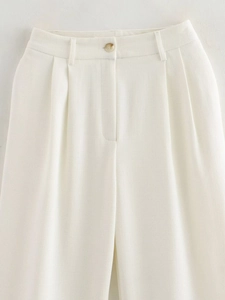 Detail of white trousers waist featuring beige button, belt loops, and pleated texture