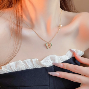 Close-up of golden butterfly necklace with pearl accent on elegant female model