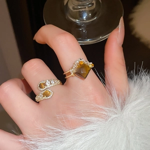 Close-up of golden tiger eye stone rings with zircon accents on a model hand