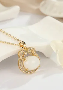 Vue détaillée d'un pendentif doré irrégulier avec cabochon blanc et oxydes de zirconium