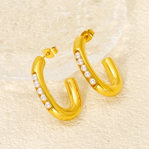 Elegant gold U-shape hoop earrings featuring embedded white pearls on a textured background
