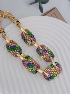 Close-up of retro chunky gold necklace featuring rainbow crystal encrusted pig nose links