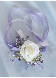Detail of white artificial rose wedding wrist corsage with purple ribbons and lavender