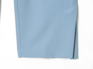 Dettaglio dei pantaloni blu nebbia con spacco laterale sull'orlo e trama del tessuto tessuto