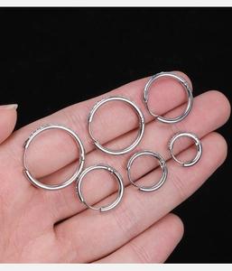 Primo piano di cinque misure di orecchini a cerchio in argento con diamanti nella mano