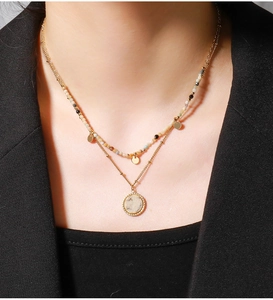 Detail showing layered gold brass necklaces with colored beads and stone pendant on model