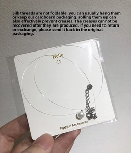 Macro detail of natural pearl necklace with invisible fish line and lobster clasp on card