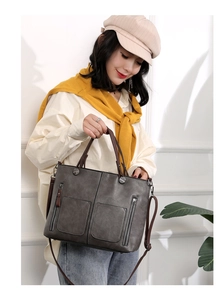 Detail of dark grey PU tote bag featuring twin front zipper pockets and silver hardware