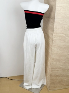 Back view of black bandeau top with red trim and white wide-leg sweatpants on a mannequin