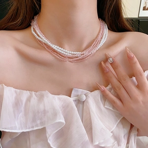 Close-up of bohemian multilayer pearl and pink crystal bead necklace worn by a model