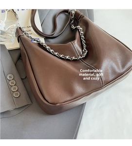 Close-up of dark brown leather tote bag with fine stitching and metallic chain detail
