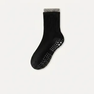 Close-up of black cotton yoga socks showing anti-slip silicone dots and ribbed cuffs