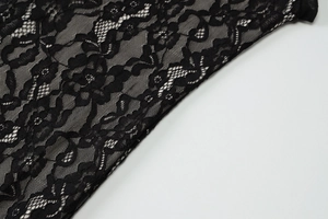 Close-up of intricate black floral lace texture and sheer mesh on a slim dress