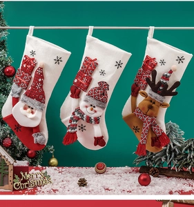 Close-up of three Christmas stockings with 3D Santa, Snowman and Reindeer hanging on green wall