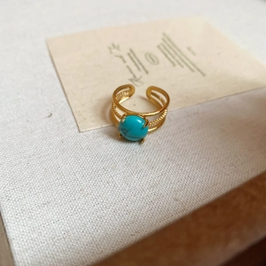 Close-up of 18k gold plated open ring featuring a round turquoise stone and triple band design
