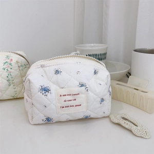 Détail d'une trousse à maquillage en coton matelassé avec imprimé floral vintage