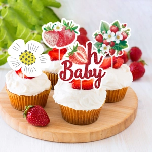 Close-up of strawberry cake toppers with red glitter Oh Baby sign and floral patterns