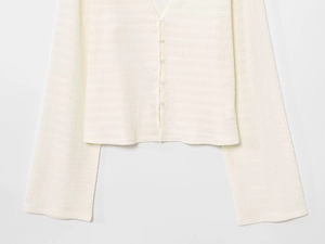 Dettaglio del cardigan in maglia crema con trama a nido d'ape e ampi polsini a coste