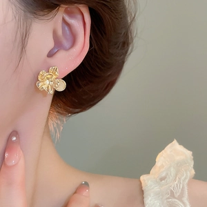 Macro view of gold flower earrings with opal center worn on ear for elegant style