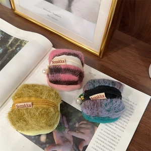 Macro detail of plush earphone pouches with zipper, pearl charms and woven label