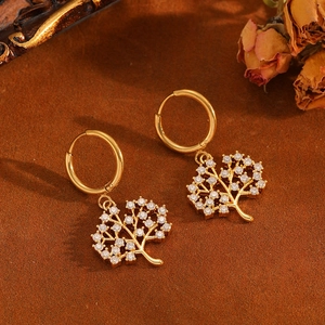 Detail of gold tree of life hoop earrings with sparkling crystals on velvet background