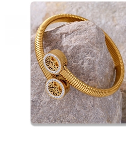 Macro view of gold Tree of Life open bangle with crystals on natural grey rock background