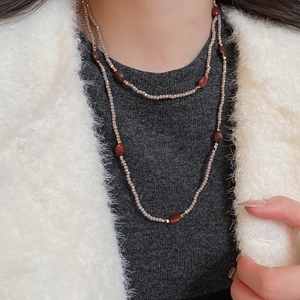 Detail of tiger eye beaded necklace with red accents and golden spacer beads on a model