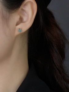 Macro shot of S925 sterling silver flower earring with blue zircon on female model's ear
