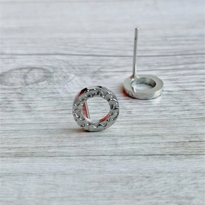 Detailed view of silver stud earrings with hammered texture and geometric round shape