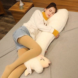 Young woman hugging a long white alpaca plush body pillow in a cozy bedroom setting