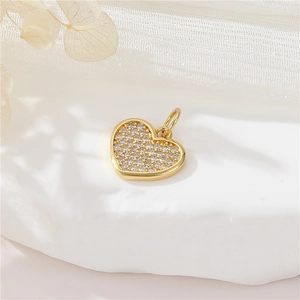 Macro shot of gold heart-shaped pendant paved with sparkling zircons for jewelry making