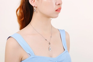 Close-up of leaf-shaped silver necklace and zircon earrings worn by a model