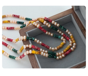 Detail of freshwater pearl and colorful stone necklace in a wooden jewelry box