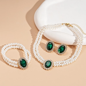 Three-piece luxury jewelry set featuring emerald stones, pearls, and gold finish