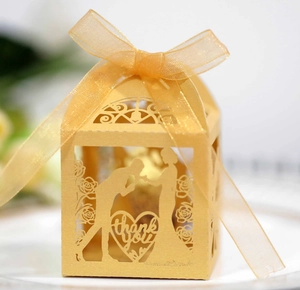 Golden laser-cut wedding favor box with heart silhouette and elegant ribbon bow