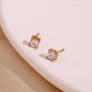 Macro view of gold stud earring featuring a round clear zircon in a four-claw setting