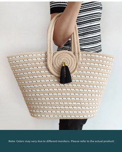 Detail of striped woven tote bag featuring reinforced handles and black tassel charms