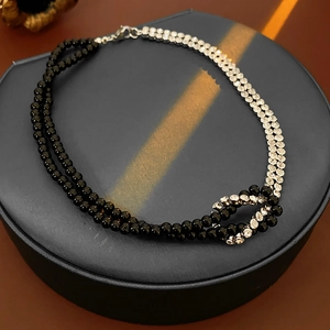 Detail of double-layer necklace with black beads, silver rhinestones and central knot design