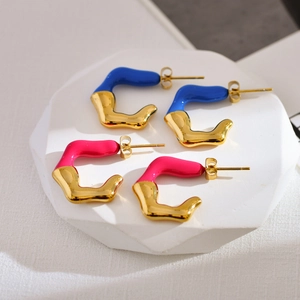 Detail of gold-plated irregular C-shaped earrings with blue and pink enamel finish