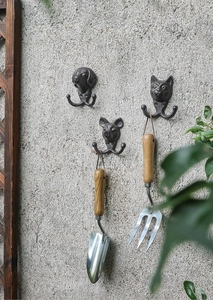 Detail von Vintage-Gusseisen-Tierhaken mit Hund- Schwein- und Katzendesigns an der Wand