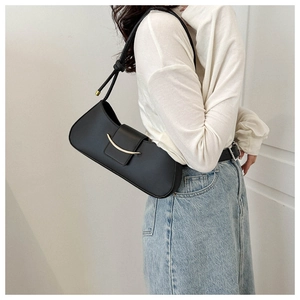 Model wearing black leather hobo bag with a sleek gold metal curve accent